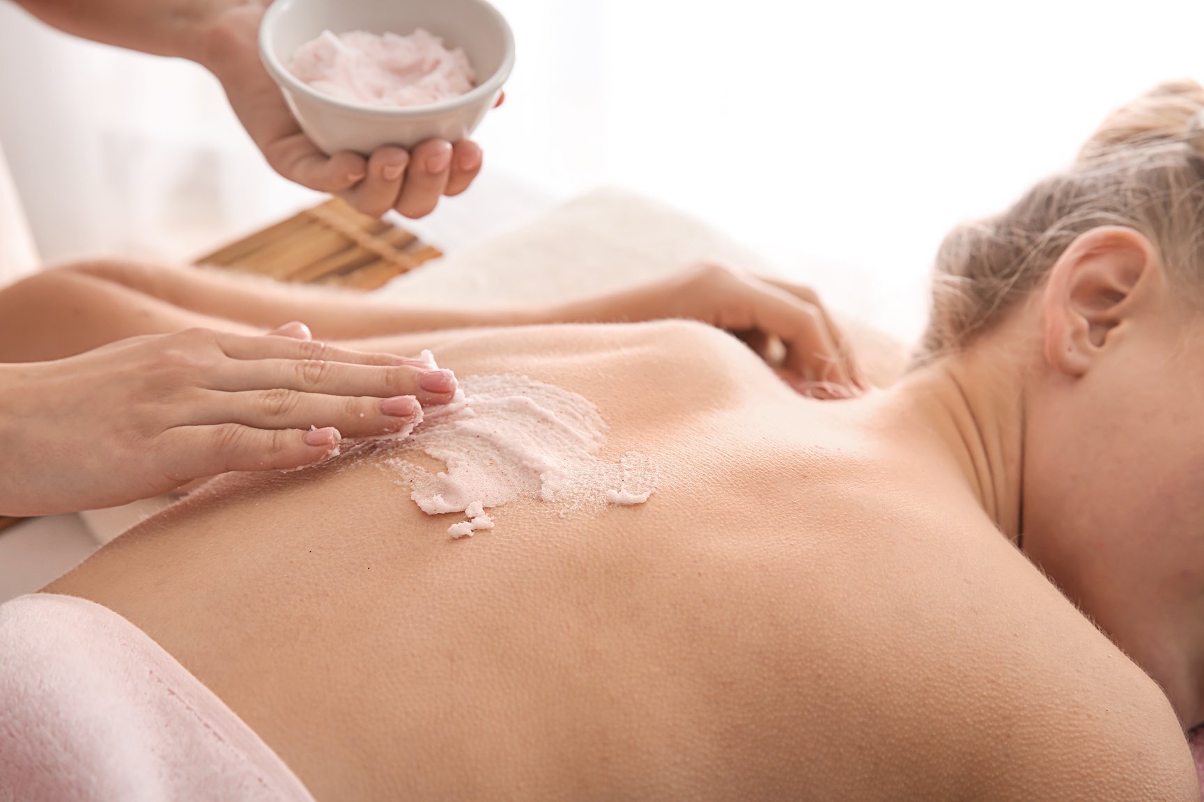 Young Woman Undergoing Treatment with Body Scrub in Spa Salon